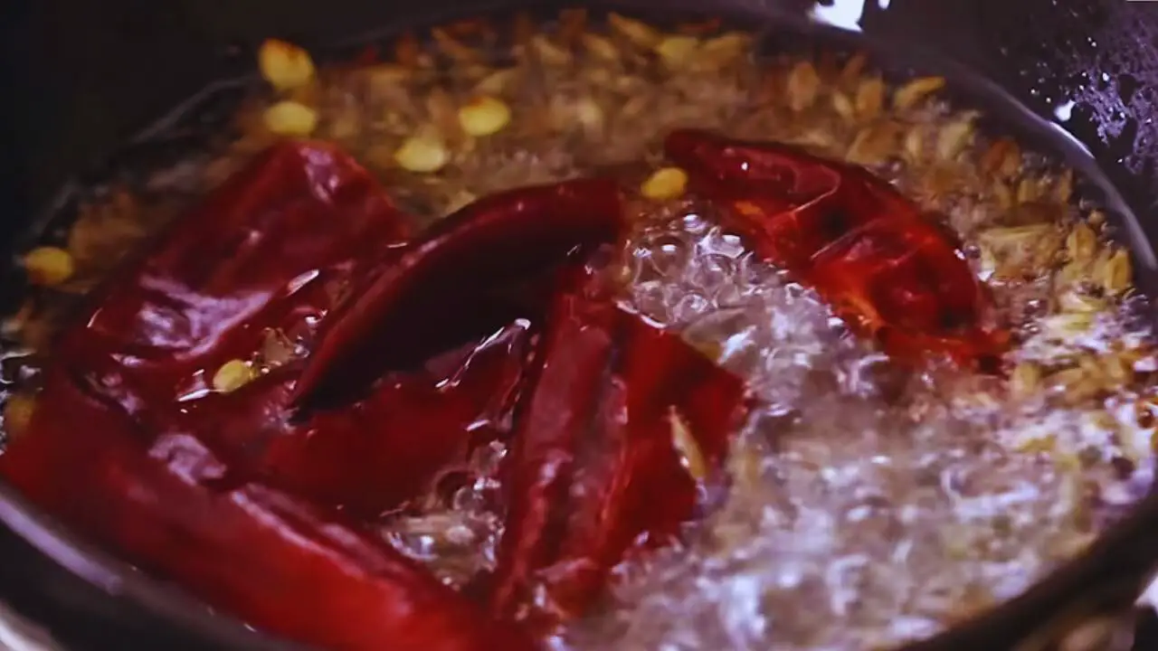 Adding dry red chilies to peanut chutney tadka 