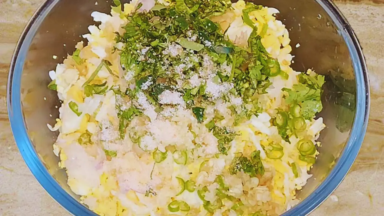 Adding green leaves to Egg Cutlet ingredients