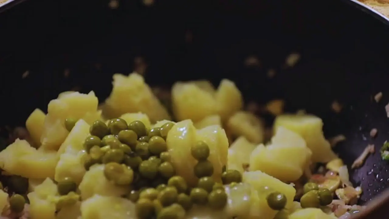 Adding potatoes and green peas 
