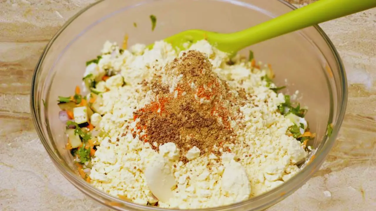 Adding powder ingredients to make the Vegetable Pakora mixture