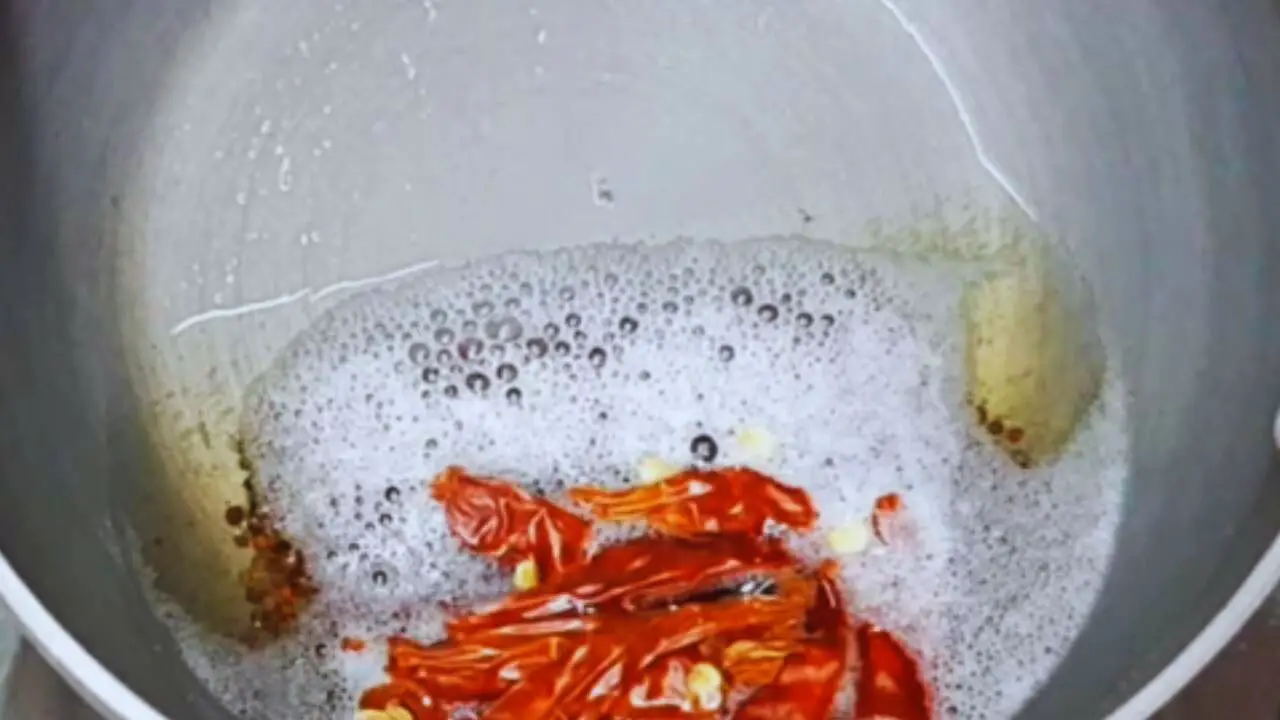 Adding red chilies to the tadka for Dahi Chutney