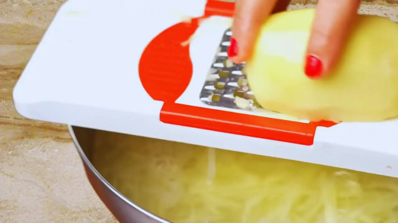 Grating potatoes to make Aloo Pakora