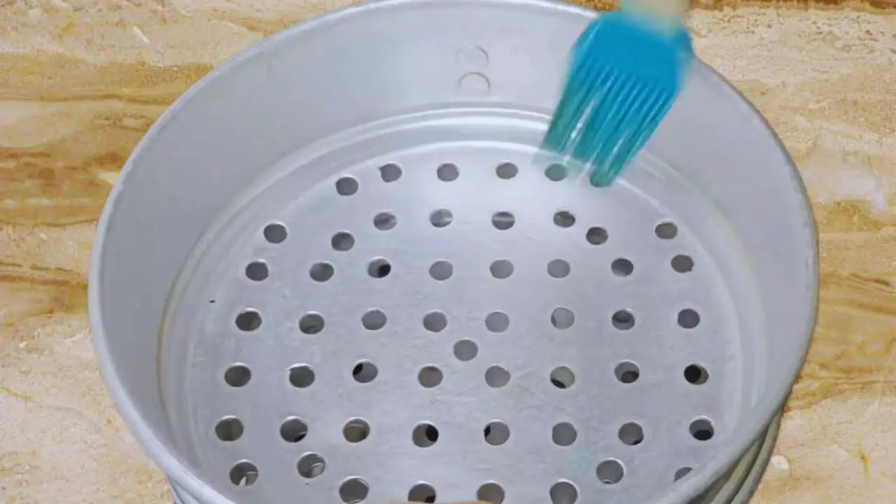 Greasing the steamer for making steam Fish Momo