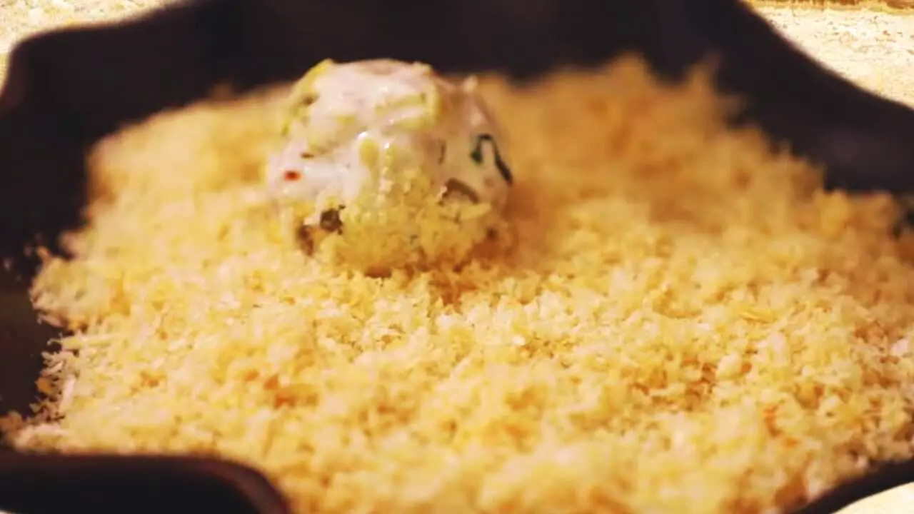 Putting Fish Balls on plate with bread crumbs 