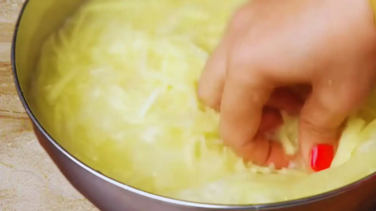 Washing grated potatoes to make Aloo Pakora