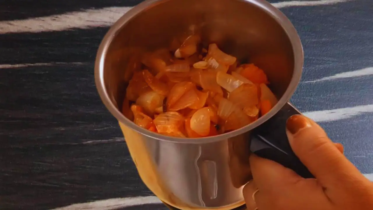 Transferring cooked onion and tomatoes to a mixer 