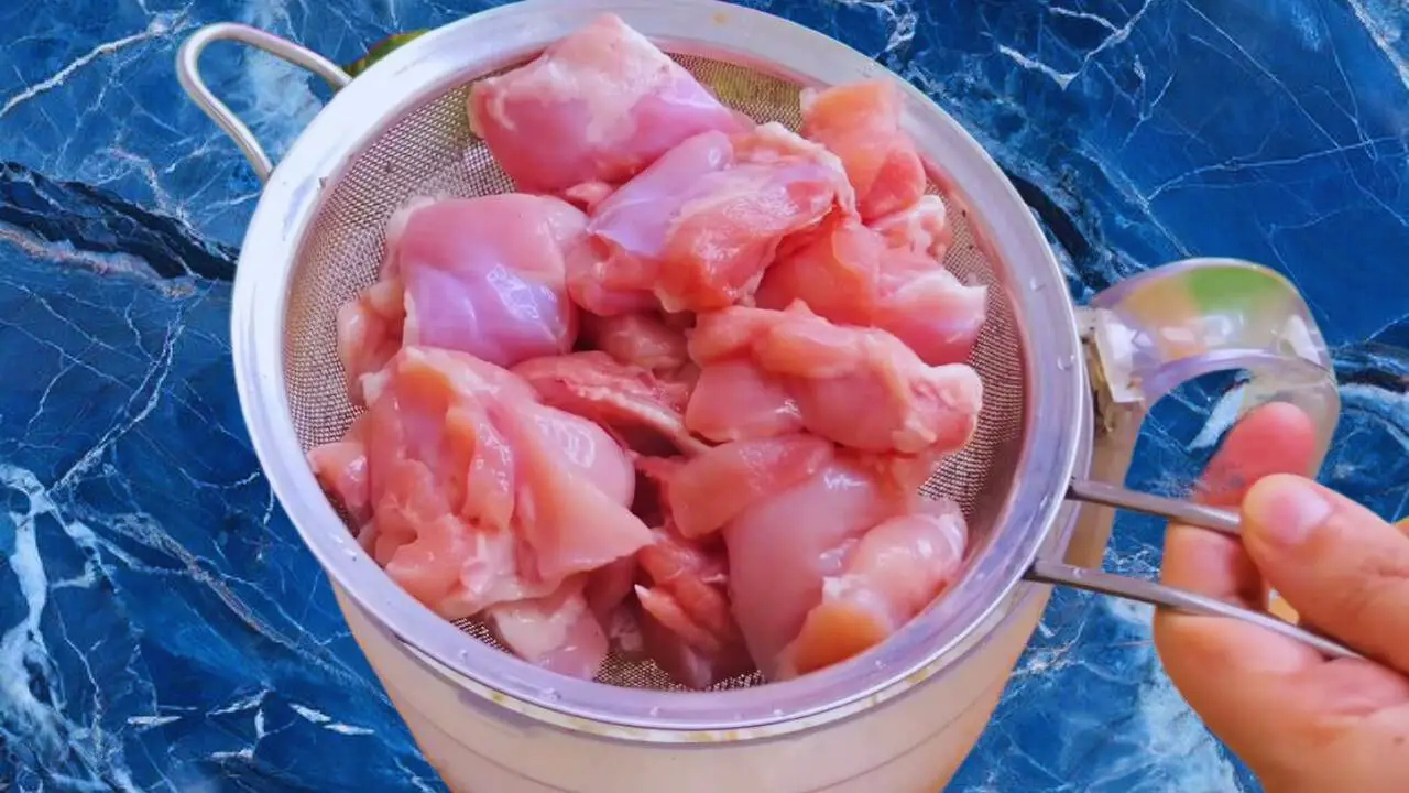 Straining washed chicken pieces 